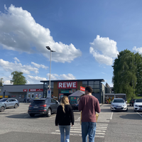 "Zwei Personen auf dem REWE-Parkplatz."