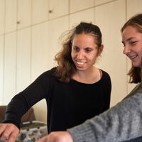 zwei weibliche Personen stehen lächelnd nebeneinander und spielen am Aktivtisch