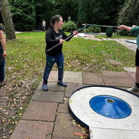 "Maya berührt beim Minigolfen mit ihrem Schläger mit einem anderen Schläger."